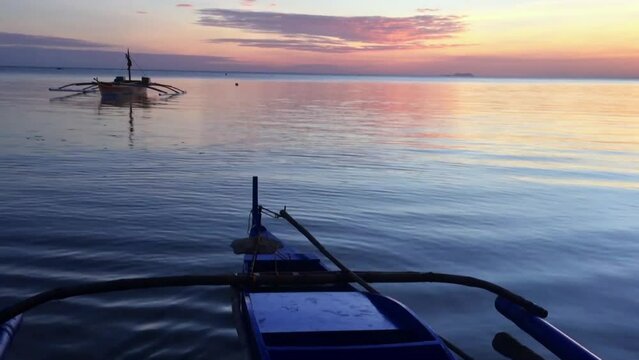 Onboard the traditional Filipino boat watching the beautiful sunset on Siquijor Island. The sky is colorful at sunset with dark blue water in the evening.