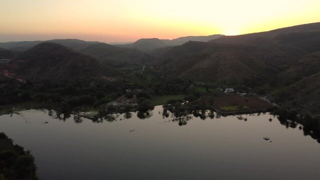 Aerial Flying Over Fateh Sagar Lake With Golden Orange Sunset On Horizon In background. Push Forward, Tilt Up