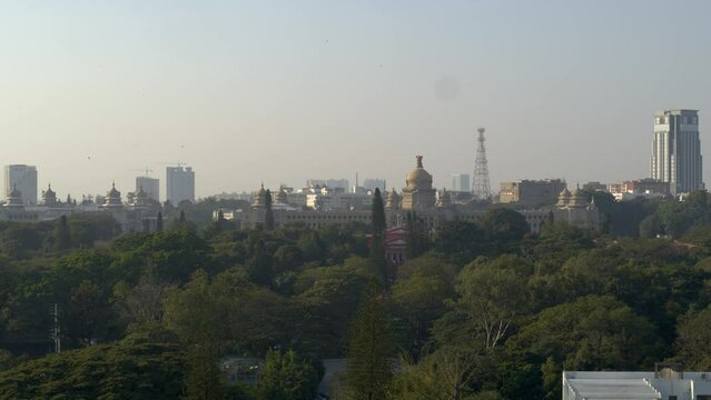 Aerial View From Cubbon Park On Hazy Day In Bangalore With Dome Top Of Vidhana Soudha Seen In background. Descending Shot
