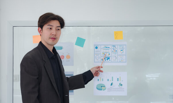 Portrait business man one oerson  Asian stand presentation holding pen and looking creative write note plan maketing idea project ready happy working online sale inside home office with intention