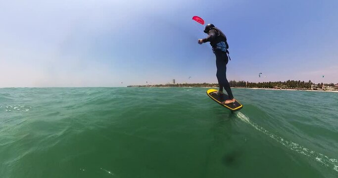 Young man kite surfing hydro foil near coastline of Thailand, back view