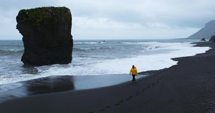 A Tourist Walking On The Shore Of L&aelig;kjavik Black Sand Beach On The South Coast of Iceland. Aerial Shot