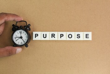 hand holding a clock and alphabet letters with the word purpose