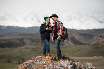 Happy two girls travelers stand on rock in mountains - 766807637