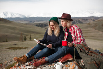 Two traveler girls with map sitting on rock in mountains - 766807858