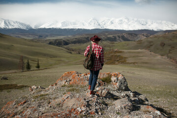 Hipster girl traveler with hat and backpack on background of mountains - 766808417