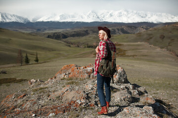Hipster girl traveler with hat and backpack on background of mountains - 766808446