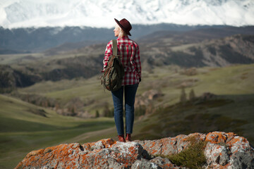 Hipster girl traveler with hat and backpack on background of mountains - 766808690