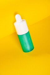 Blue glass cosmetic bottle, Skin care or sunscreen cosmetic on yellow background.