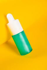 Blue glass cosmetic bottle, Skin care or sunscreen cosmetic on yellow background.
