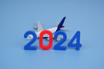 Numbers 2024 and airplane on blue background.	Transport in 2024 concept.