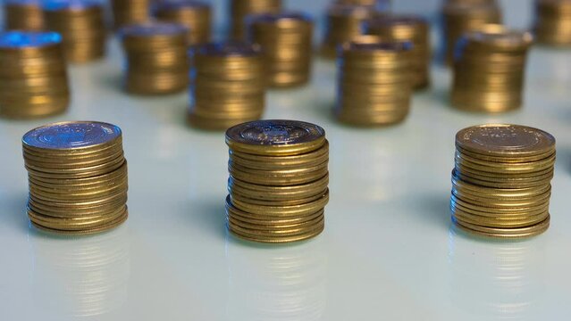 A table with 3 stacks of gold coins that increase and then decrease. Money returns time lapse