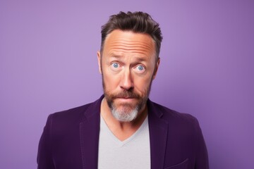Portrait of a surprised mature man looking at camera on violet background