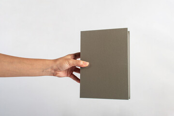 Blank grey book cover in hand on white background.