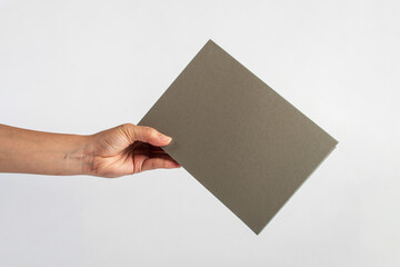 Blank grey book cover in hand on white background.
