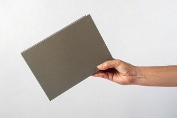 Fototapeta premium Blank grey book cover in hand on white background.