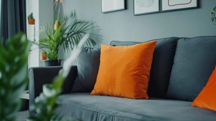 Orange pillow on dark grey sofa in modern apartment interior