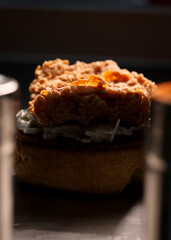 Savor the Flavor: Indulge in the irresistible allure of our specialty hamburger bun paired with crunchy golden-brown chicken and a touch of spiciness from the adjacent hot sauce in this captivating st