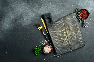 Black stone kitchen background with spices, herbs and kitchen utensils. Free space for text. Top view. Rustic style.