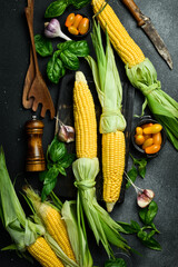 Fresh vegetables, herbs, ripe corn and spices on a black stone background. Organic food. Top view.