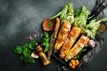 Grilled corn with spices and sauces on a black stone background. Barbecue. Organic food. Top view.