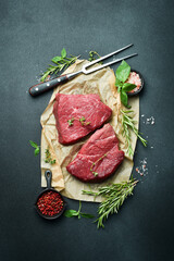 Juicy raw veal with steak spices on a stone background. Veal, meat. Top view.