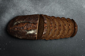 Rye sourdough bread with flax cut on a board. Fresh bread on a black background. Top view.