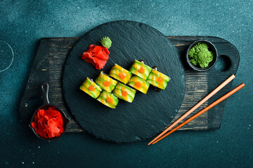 Sushi with black rice, fish and avocado on a rustic dark background. Sushi rolls, nigiri, maki, pickled ginger, wasabi, soy sauce. Sushi set on a table.
