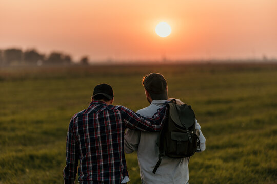 Two fashionable males embarking on a countryside hike at sunset