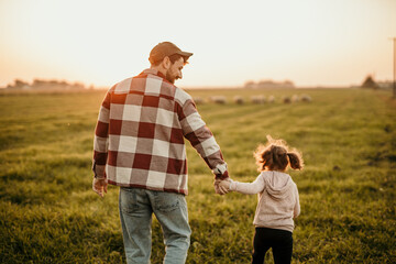 Father and daughter watching the sunset in their rustic farm field