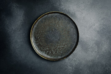 Top view of dark stone plate on black background. Creative advertising photo. Free space for text.