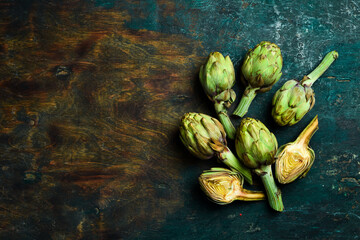 Green artichokes on an old wooden table. Healthy food.