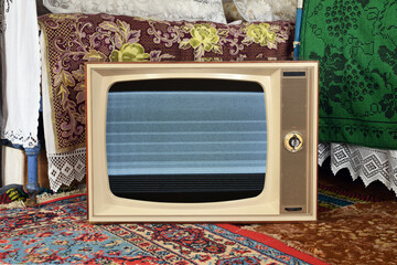An old vintage TV with interference and noise on the screen in a rustic interior.