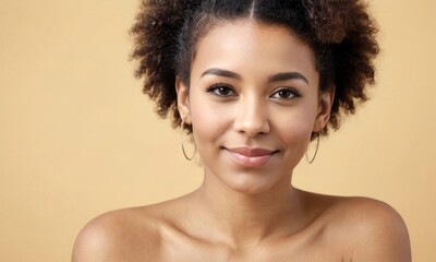 African american dark skinned young woman with curly hair is smiling at the camera. She has a natural, relaxed look on her face. Portrait over beige background