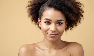African american dark skinned young woman with curly hair is smiling at the camera. She has a natural, relaxed look on her face. Portrait over beige background - 766849274