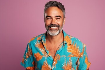 Portrait of a handsome middle-aged man in a colorful shirt on a pink background
