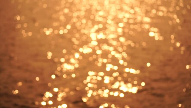 Abstract Blurred video screensaver bokeh golden sea at sunset. The sun reflects and sparkles on the waves.