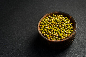Close-up of mung beans in a ceramic bowl. Superfood On a dark concrete background.