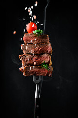 Slices of grilled meat barbecue steak Rib eye on meat fork on dark metal background close-up