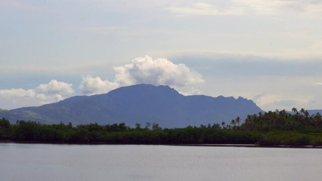 Boat ride Nadi Nausori Highlands Tourism Fiji Suva Garden Island Taveuni morning mountain peaks tropical island palm coconut tree morning cloudy blue sky calm bay shore Coral coastline parallax zoom