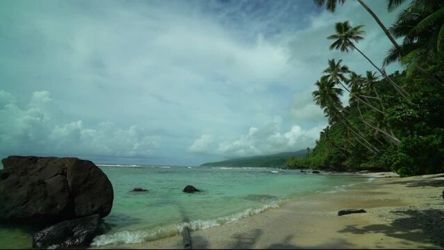 Taveuni Garden Island Tavern Falls beach walk coral sand tropical peaceful waves crashing shoreline palm coconut trees sunny blue sky cloudy boulder clear water slow pan to the right