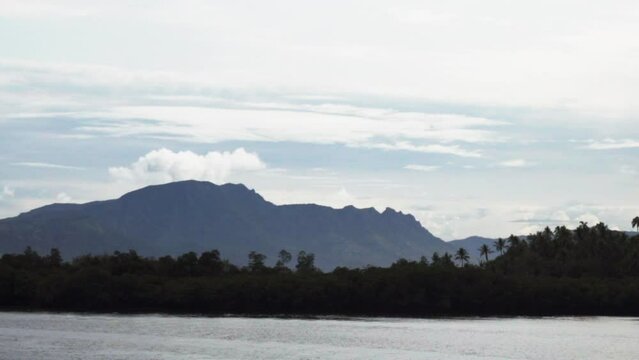 Boat ride Nadi Nausori Highlands Tourism Fiji Suva Garden Island Taveuni morning mountain peaks tropical island palm coconut tree morning cloudy blue sky calm bay shore Coral coastline zoom out