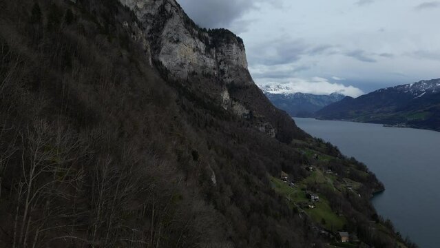 Forward drone shot of snow covered mountains with lake flowing by in Walensee, Switzerland