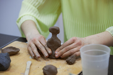 Pottery in the process of creation. A woman sculpts a figure from clay from a sculptor's workshop.
