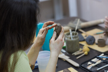 Pottery in the process of creation. A woman sculpts a figure from clay from a sculptor's workshop.