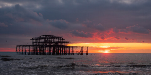 Sunset behind the ruins of the west pier on the Brighton coast east Sussex south east England UK