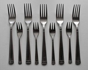 Set of three pronged and four pronged forks in a rows isolated on white surface
