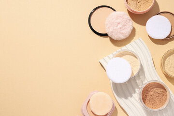 Bottles of face powder, different shades, on a pastel background.