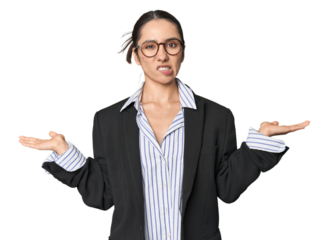 Confident young Caucasian businesswoman on studio background confused and doubtful shrugging shoulders to hold a copy space.