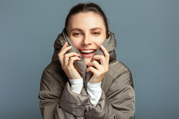 Young cheerful attractive woman wearing a grey coat during autumn and winter, isolated on grey studio background